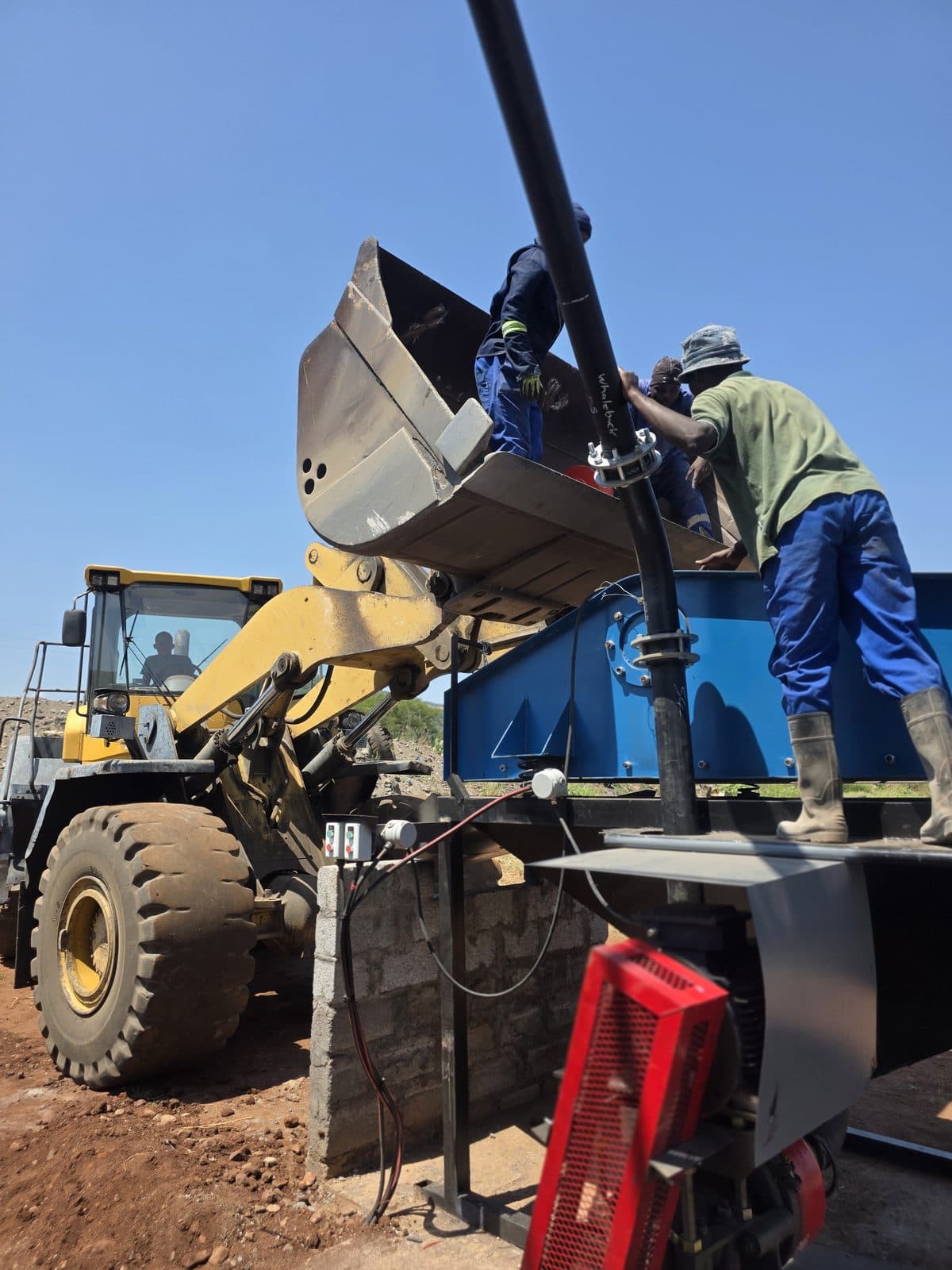 Commissioning on site, with a front-end loader charging the feed bin of the Flow Minerals washplant