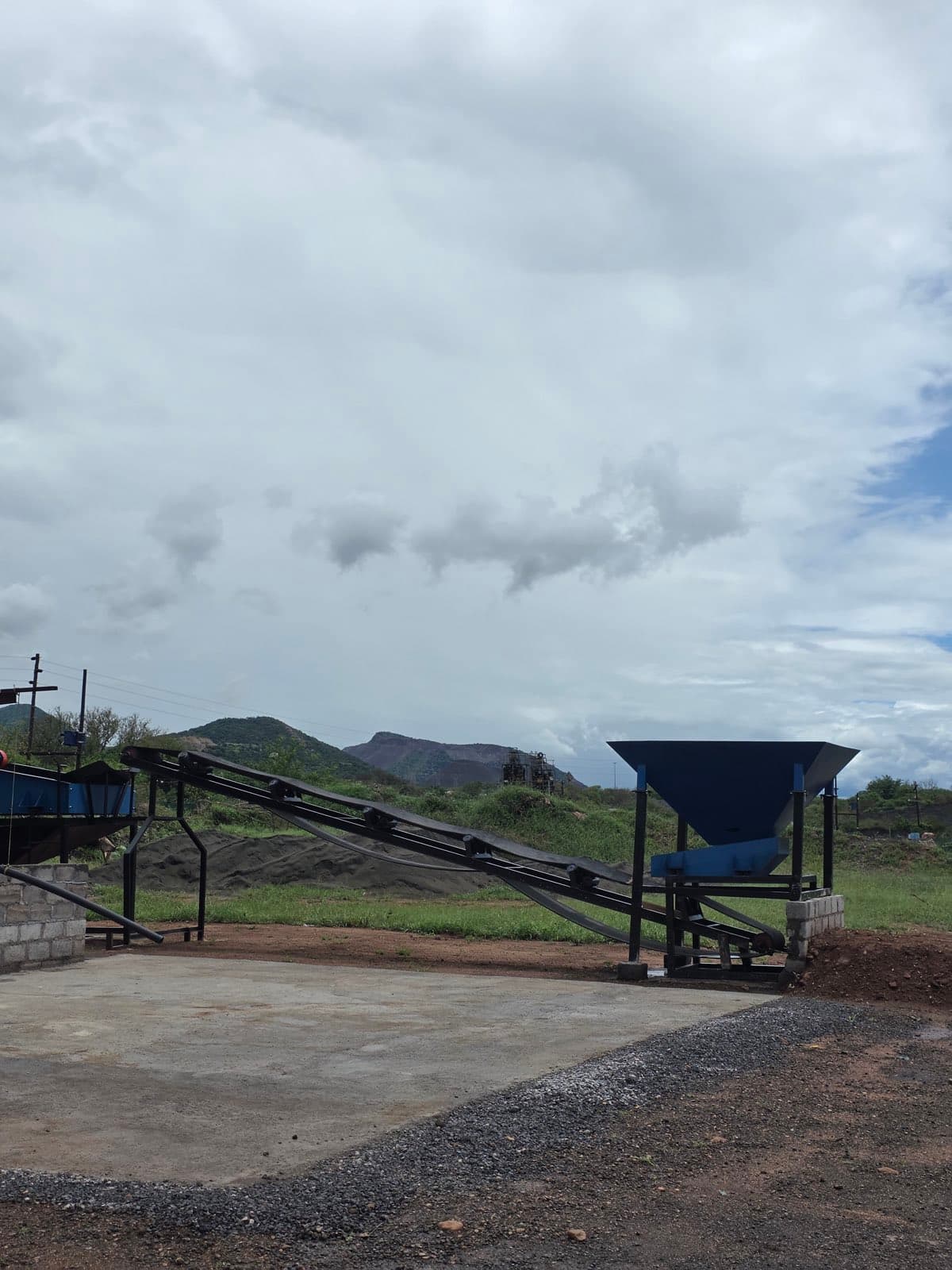 The fabricated feed bin and inclined feed conveyor installed on site at the Flow Minerals washplant, with the Steelpoort hills behind