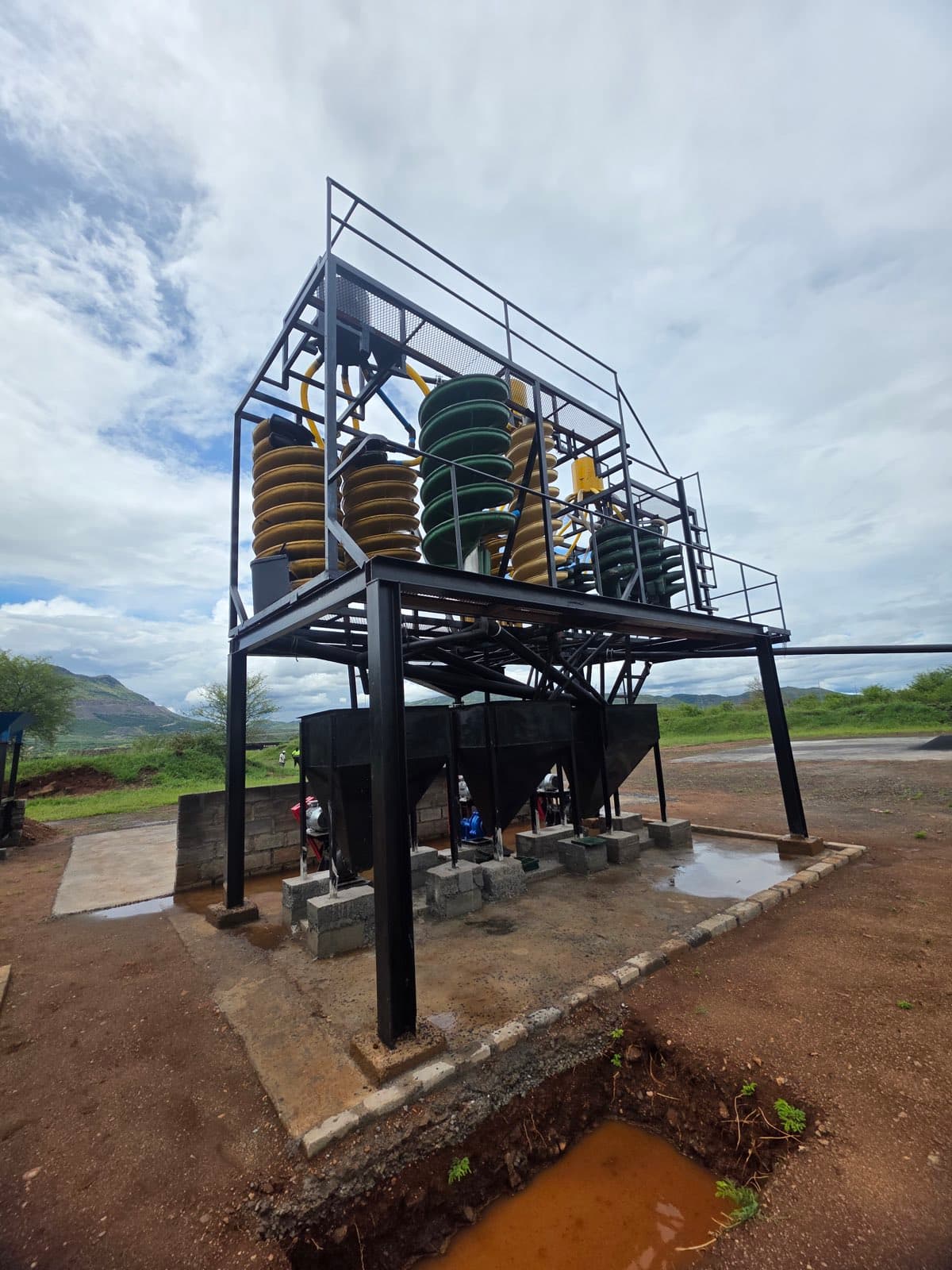 Low-angle view of the spiral support structure, with the wash bins and discharge hoppers carried beneath the spiral platform