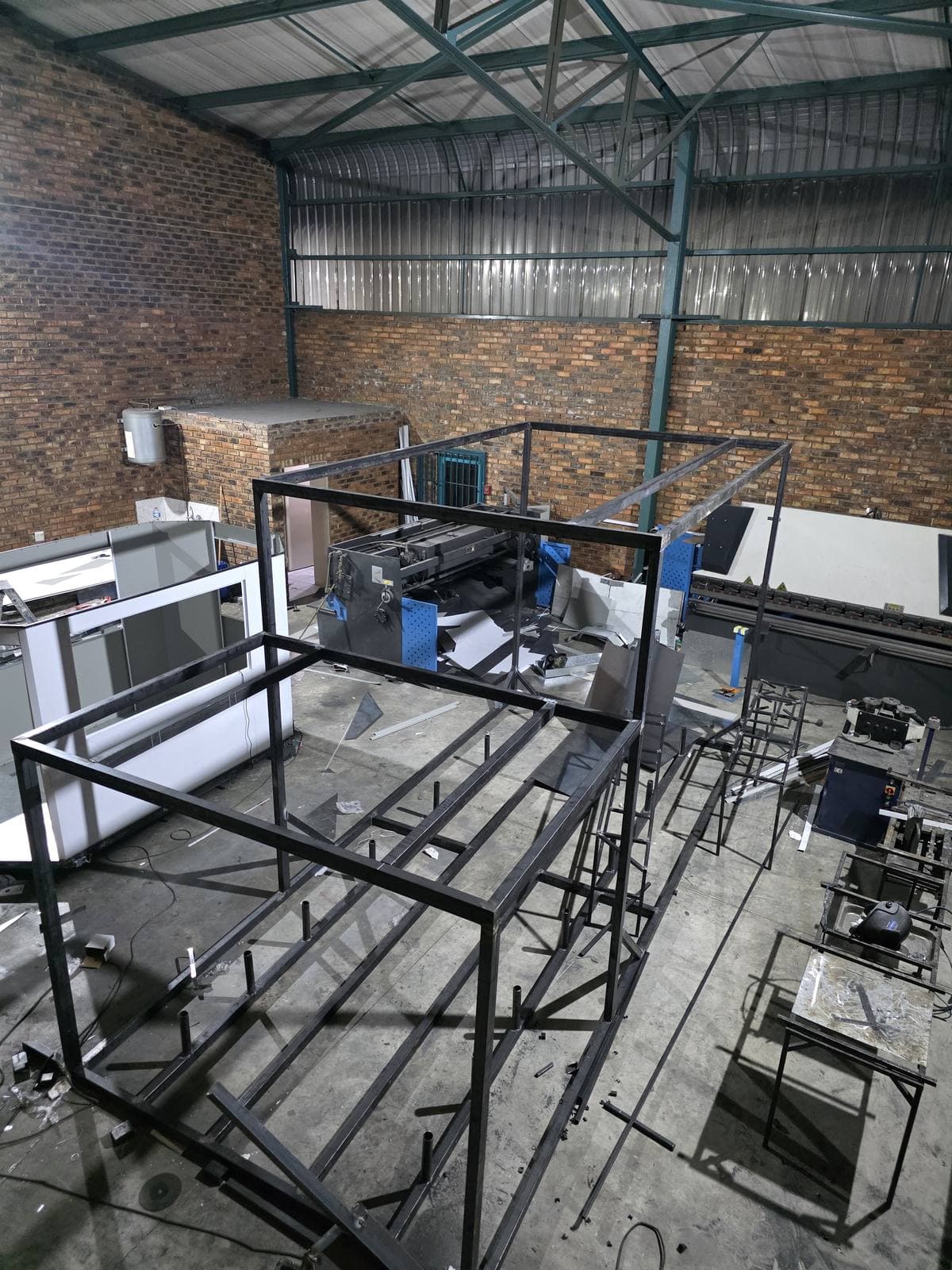 The spiral support structure frame under fabrication in the Trailored workshop, with press brakes and workbenches around it