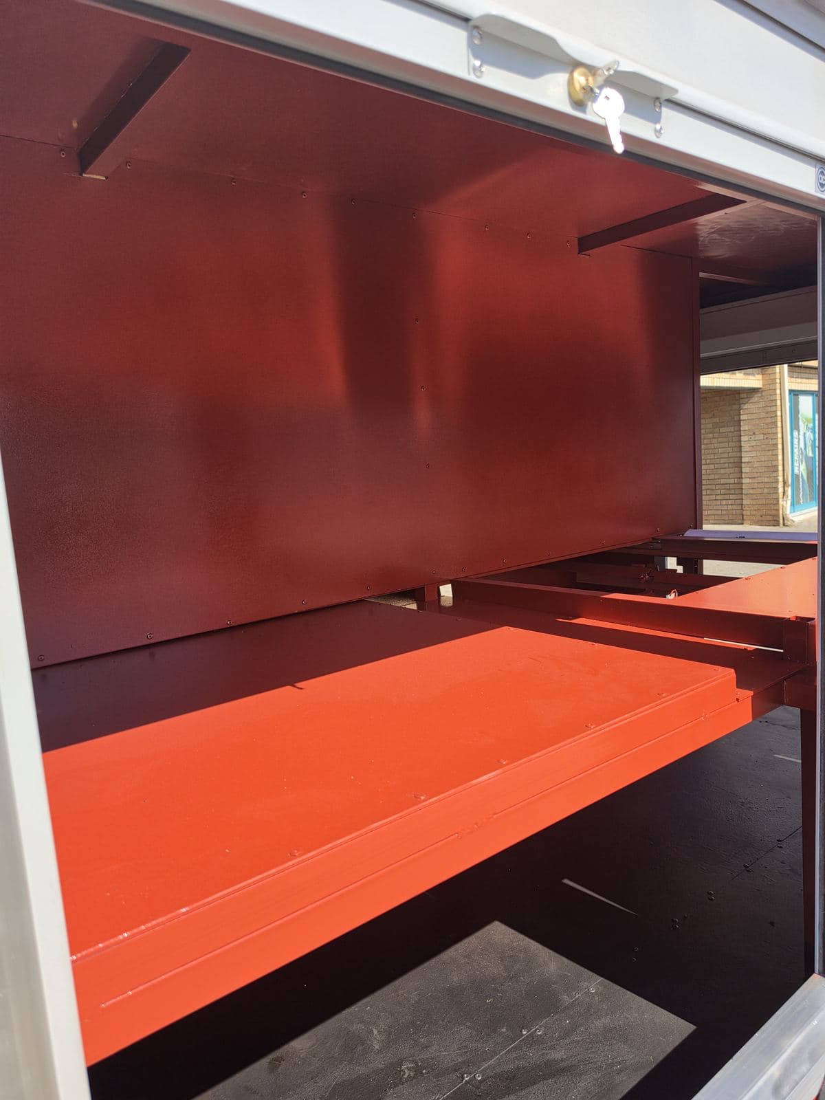 Interior compartment of the hazmat trailer with a red-painted aluminium shelf.