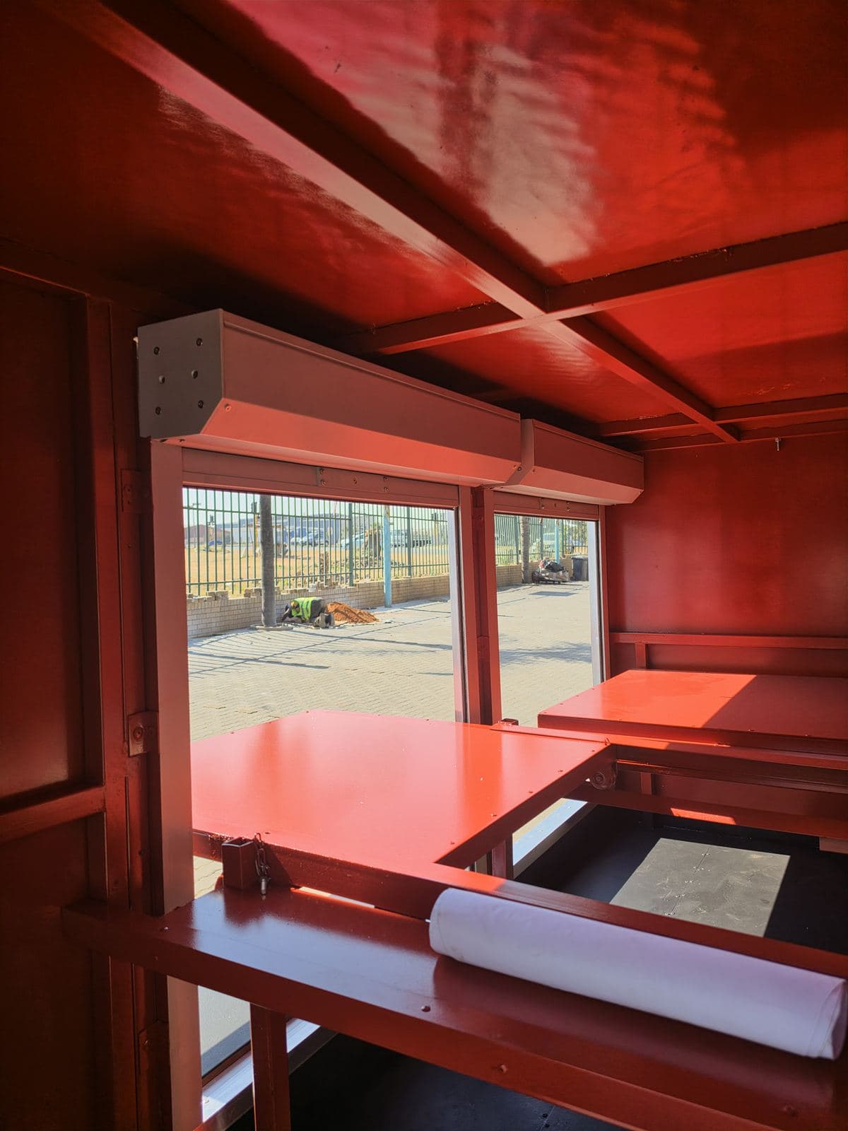 Open compartment showing an adjustable aluminium shelf painted red inside the hazmat trailer.