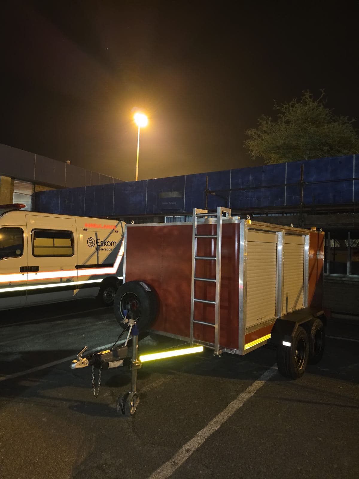 The hazmat trailer at night under yard lighting, parked alongside a site ambulance before handover.