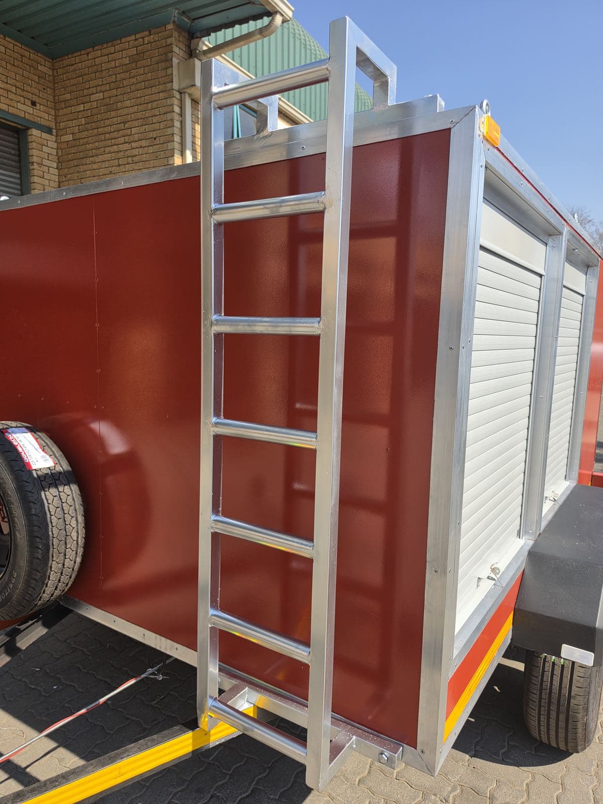 Close view of the stainless steel roof-access ladder mounted on the front panel of the hazmat trailer.