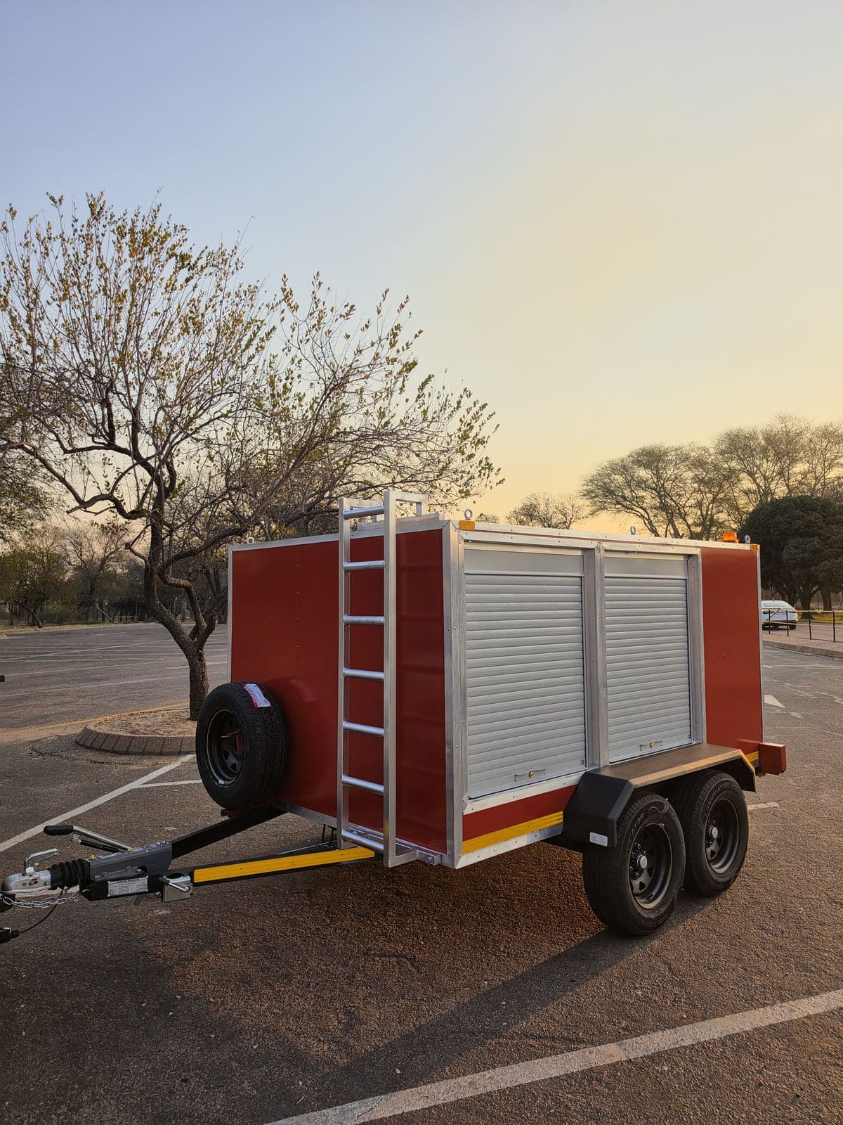 Three-quarter view of the finished hazmat trailer at dusk with the roof-access ladder on the front.