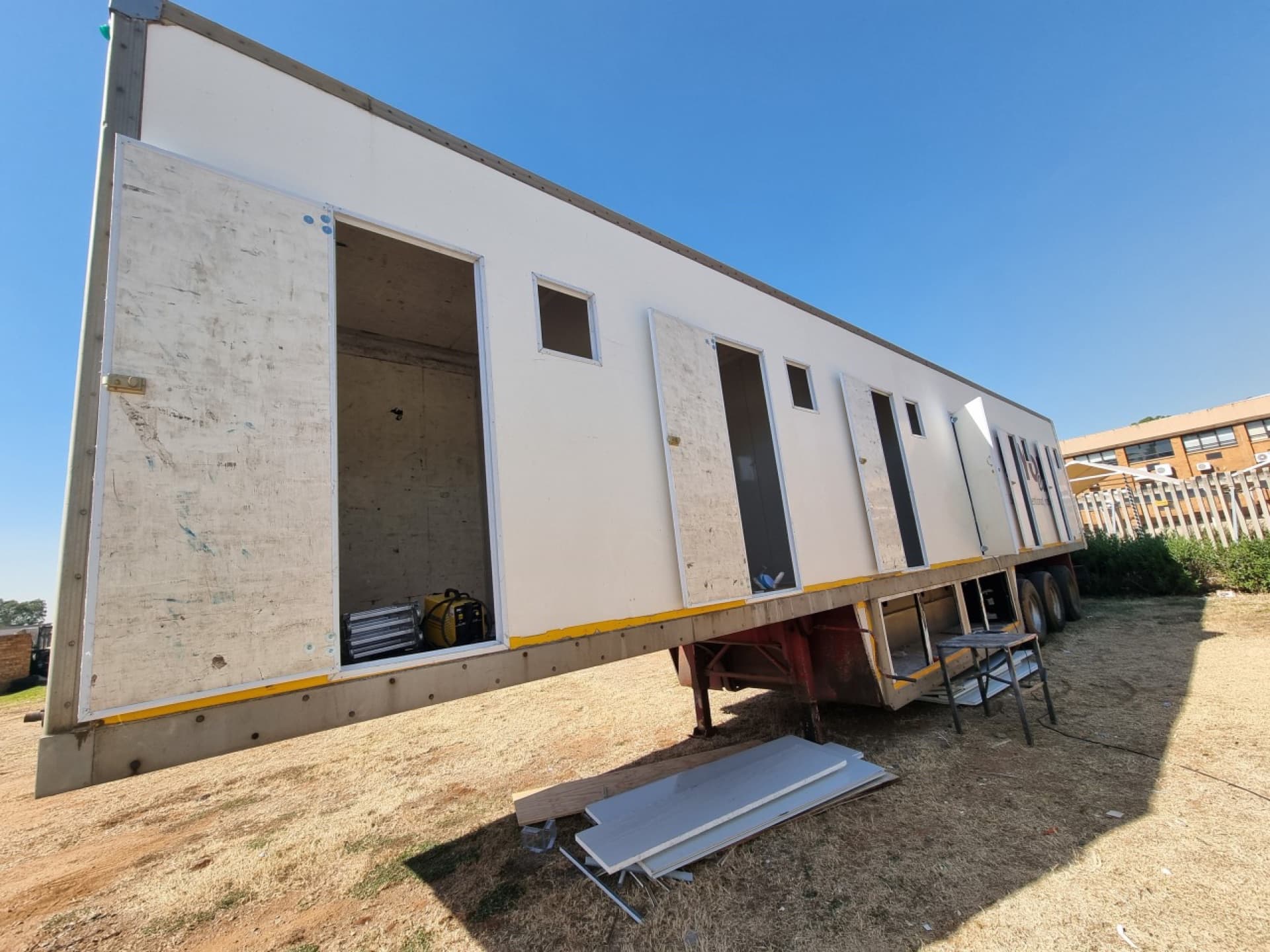 Large white melamine wall panels being installed over the plywood structure inside the trailer